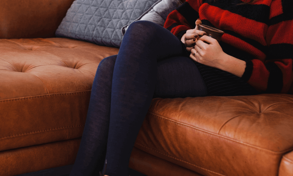 Woman wearing Merino Wool Women's Tights while relaxing on a couch with a mug in hand.